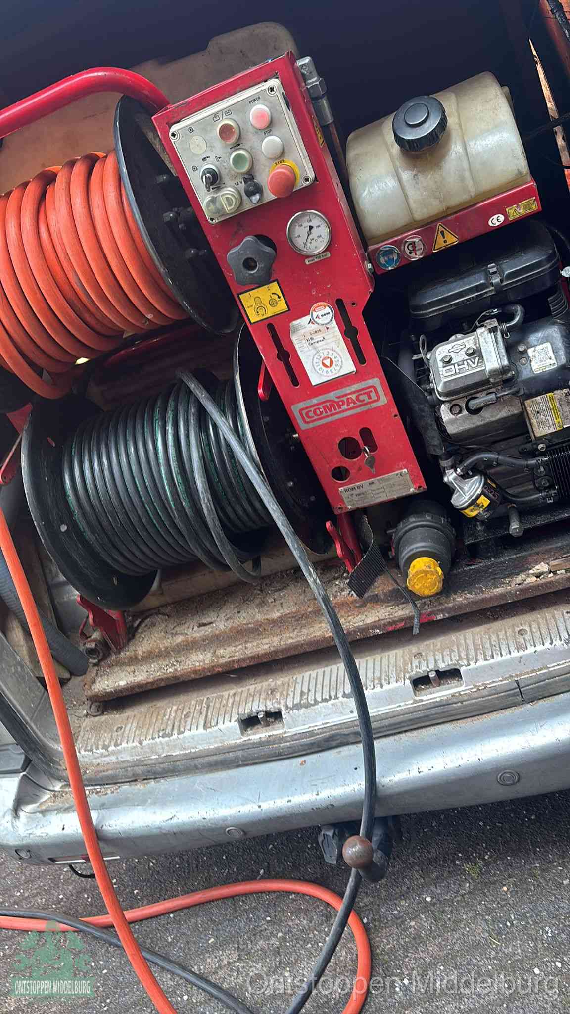 Een rood hogedruk-rioolreinigingstoestel in de laadbak van de bedrijfsbus, apparatuur voor een hardnekkige afvoerverstopping in Middelburg