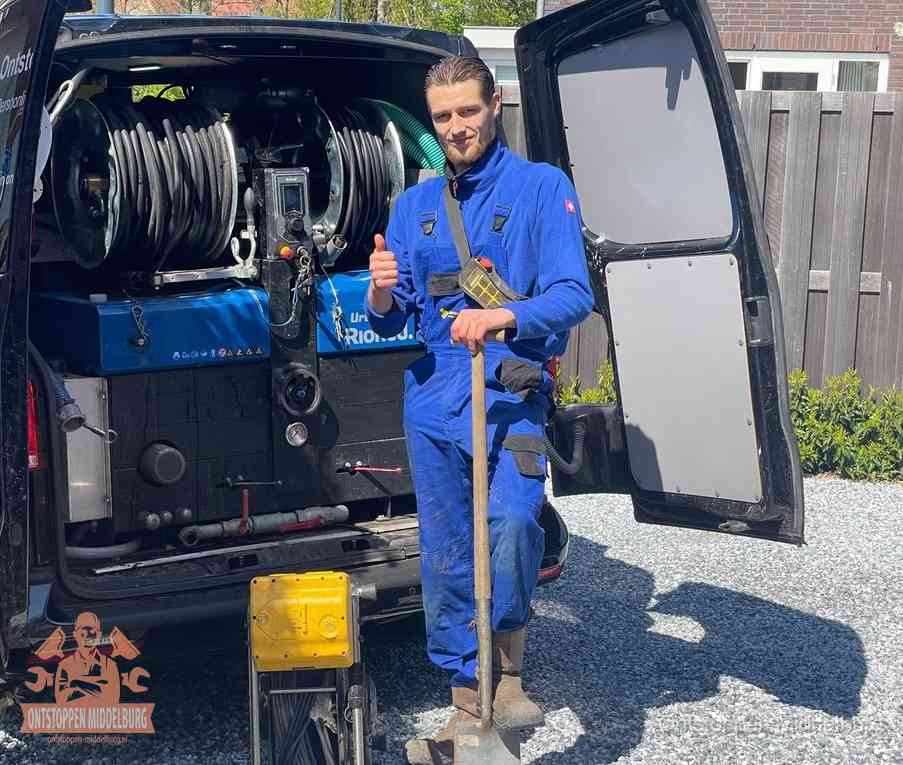 Een monteur bij de werkbus met grote hogedruk-slanghaspels, apparatuur voor hardnekkige afvoerverstoppingen in Middelburg