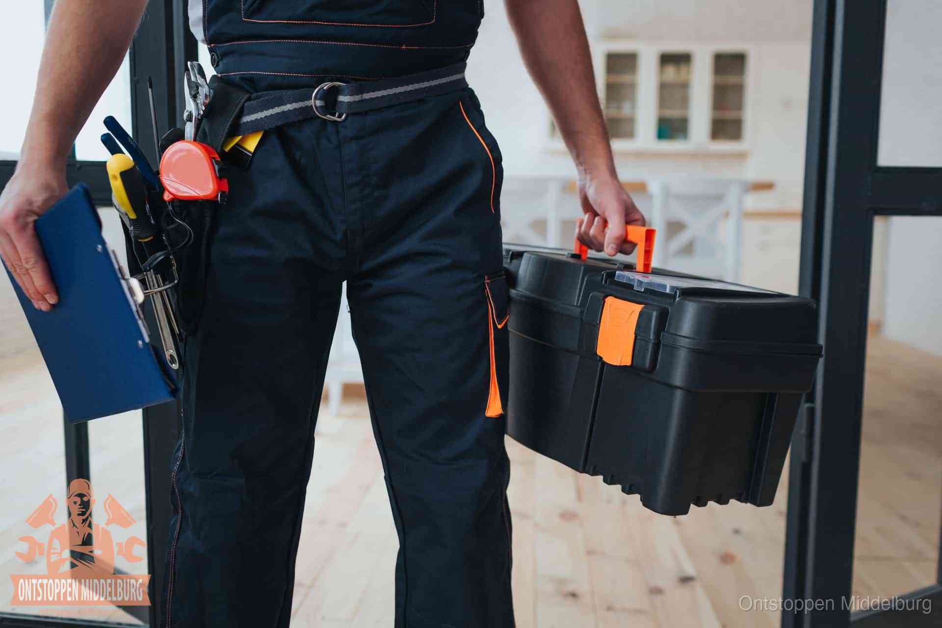 Een monteur met gereedschapsriem en klembord in een keuken, klaar om een transparante prijs voor het gootsteen ontstoppen in Middelburg te geven