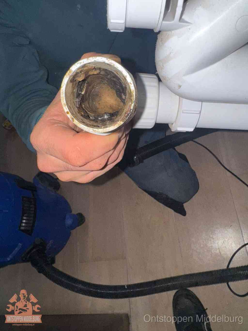 Een losgekoppelde afvoerbuis die van binnen volledig is dichtgeslibd met vet en aanslag, de meest voorkomende oorzaak van een verstopte gootsteen in Middelburg