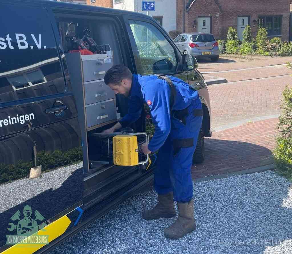 Een monteur pakt buiten op de oprit gereedschap uit de bedrijfsbus, het moment om een professional in te schakelen voor een verstopte afvoer in Middelburg