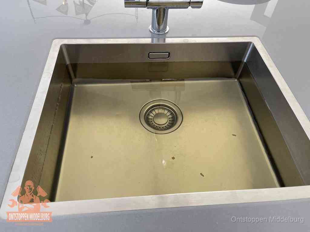 Stilstaand water in een rvs spoelbak dat niet wegloopt, een duidelijk signaal van een gootsteenverstopping in Middelburg