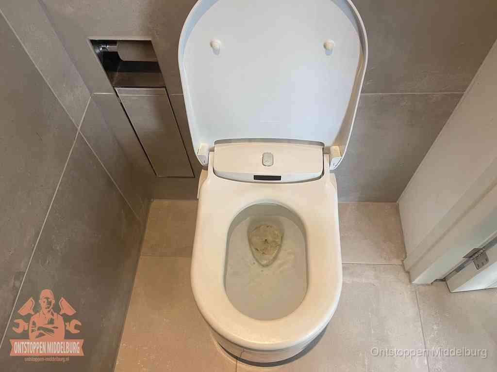 Een wit hangtoilet waarin een prop wc-papier op het water blijft drijven, een duidelijk signaal van een verstopte wc in Middelburg