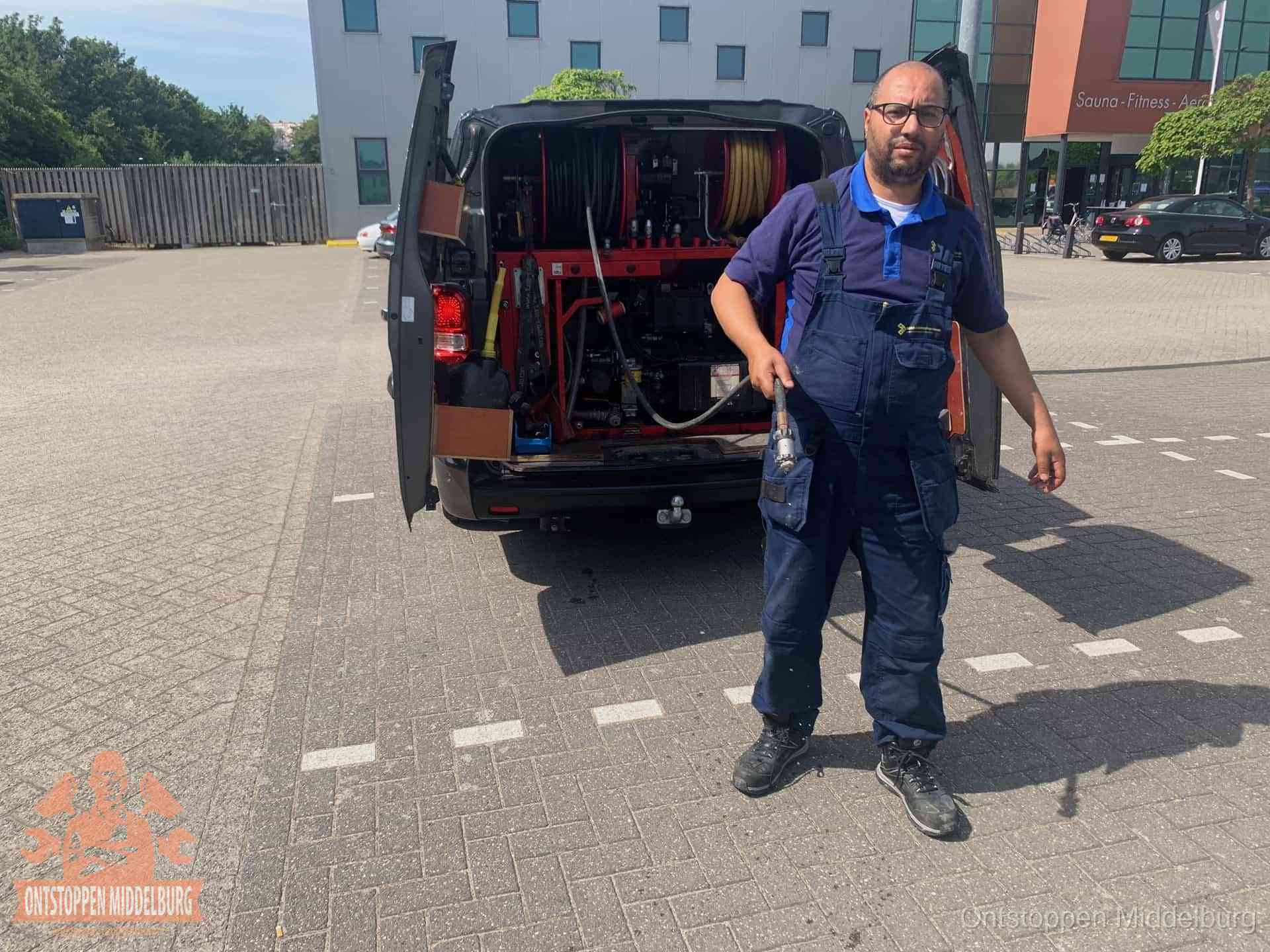 Een monteur bij zijn bestelbus met een hogedruk- en rioolreinigingsunit, klaar om de oorzaak van terugkerende wc-verstoppingen aan te pakken in Middelburg