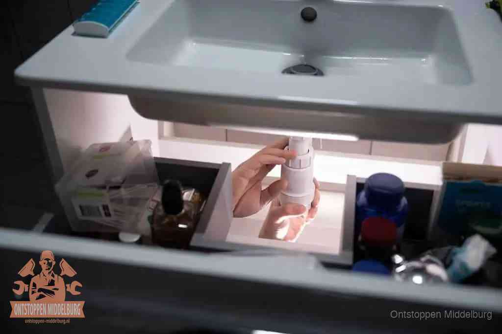 Een pompfles met zeep boven een wastafel in de toiletruimte, de warm water en afwasmiddel-methode om de wc te ontstoppen in Middelburg