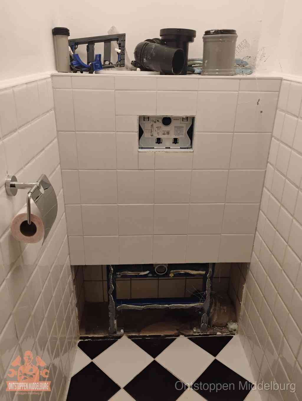 Een toiletruimte waar het hangtoilet en de inbouwreservoir-onderdelen zijn vrijgelegd voor onderhoud, periodiek nazicht voorkomt een wc-verstopping in Middelburg