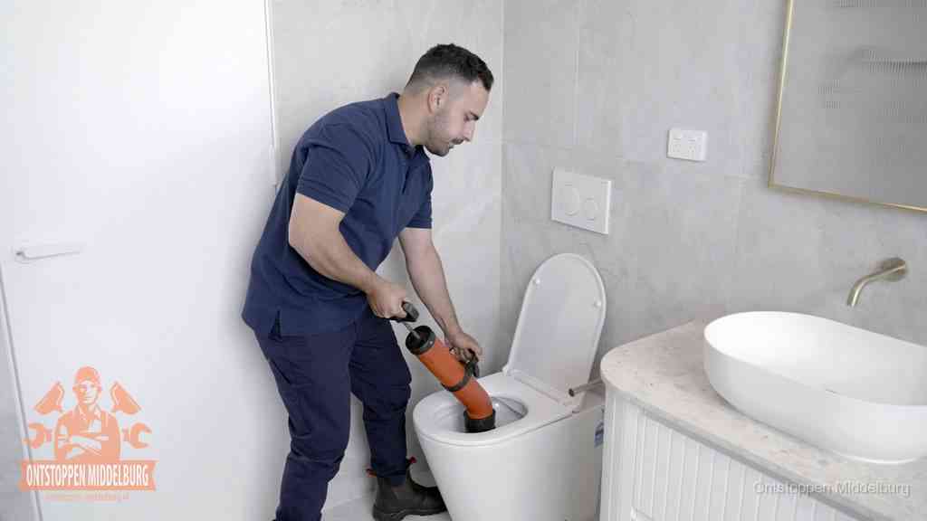 Een monteur gebruikt een handmatige perspomp (toiletontstopper) op een wandcloset tijdens het professioneel wc ontstoppen in Middelburg